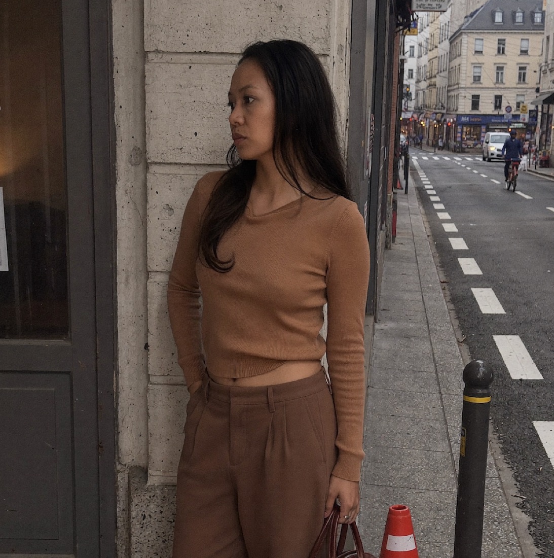 A realistic AI-generated street photo of a woman; the shop signs in the background render as gibberish